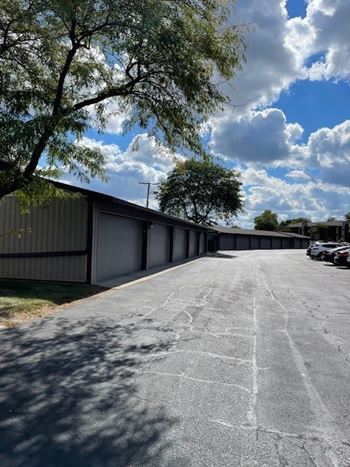 A parking lot with a building and trees in the background.